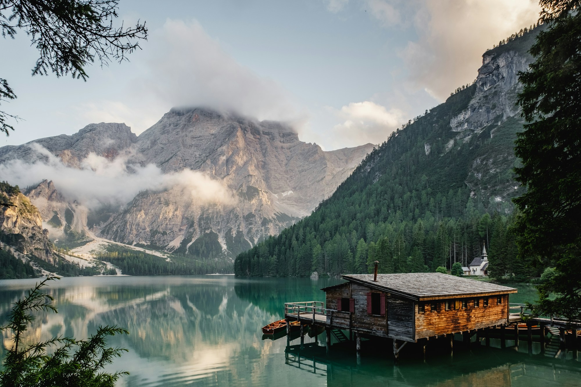A mountain lake reflecting forested slopes and a dramatic alpine landscape