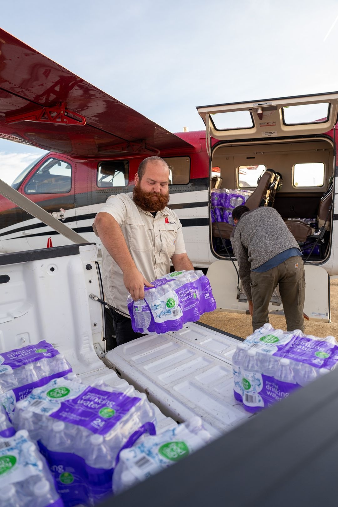 Crew members loading cases of bottled drinking water into a Redtail Air aircraft
